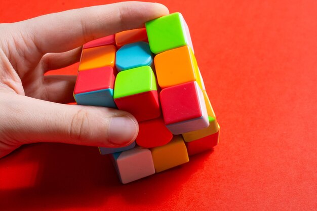 Photo cropped hand of person holding multi colored toys over yellow background