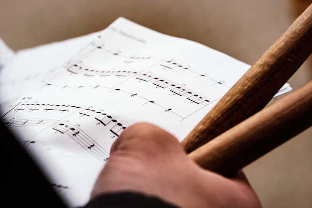 Cropped hand of person holding musical notes and drumsticks