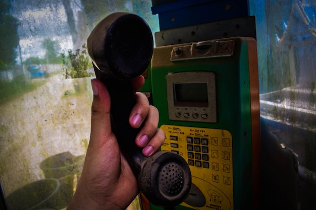 Cropped hand of person holding old pay phone