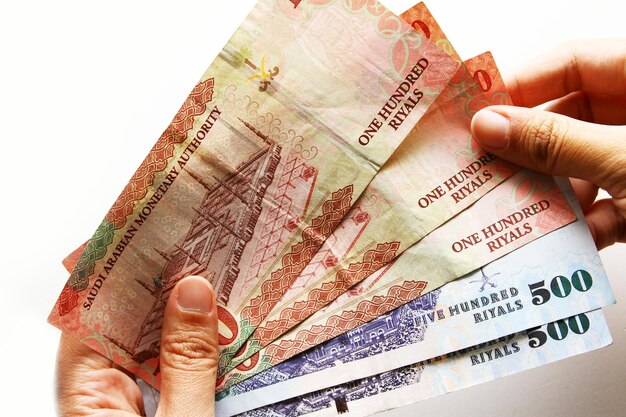 Cropped hand of person holding paper currency against white background