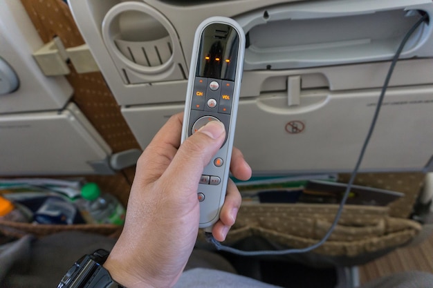 Photo cropped hand of person holding remote control in airplane