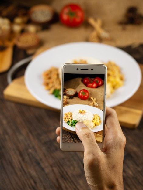 携帯電話で食べ物を撮影している人の手を切り取った
