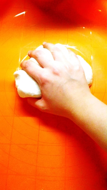 Обрезанная рука человека, готовящего тесто