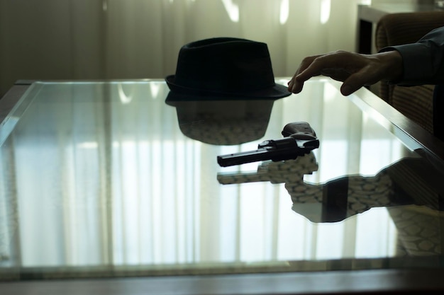 Photo cropped hand of person reaching gun on table