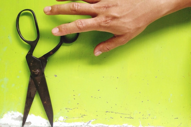 Foto mano tagliata su persona che raggiunge le forbici sul tavolo