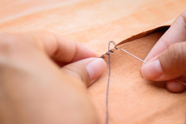 Cropped hand of person sewing fabric