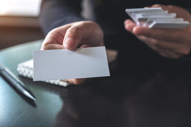 Photo cropped hand of person showing blank business card on table