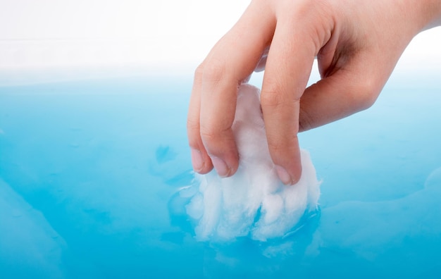 Foto mano tagliata di una persona che bagna cotone in acqua blu