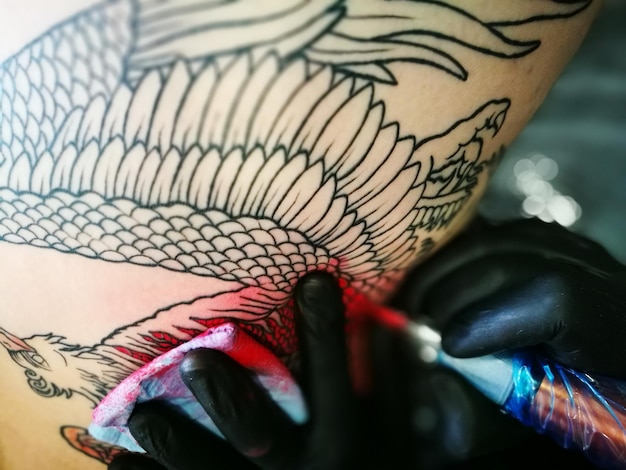 Foto mano tagliata della persona che fa il tatuaggio alla donna