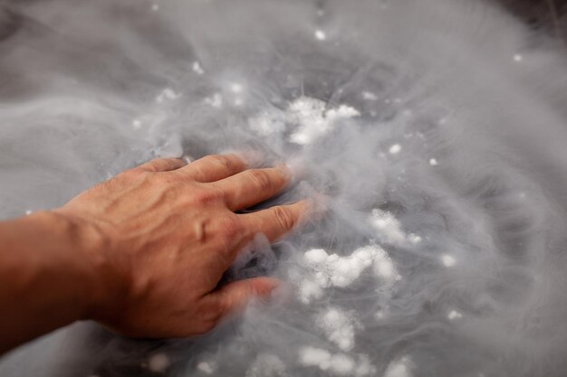 Foto mano tagliata di una persona che tocca il ghiaccio secco