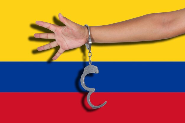 Cropped hand of person wearing handcuffs against colombia flag