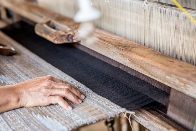 Photo cropped hand of person weaving loom on table in workshop