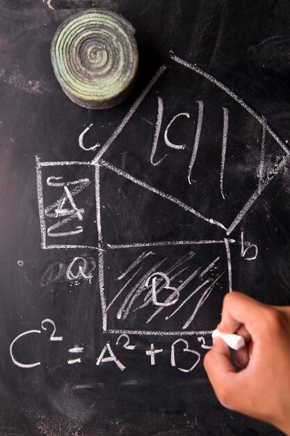 Photo cropped hand of person writing on blackboard