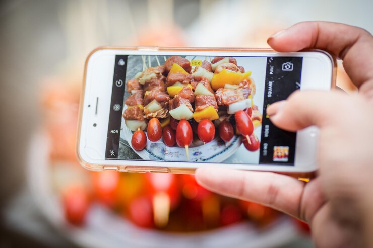 Photo 携帯電話から食べ物を写真に撮るカットされた手