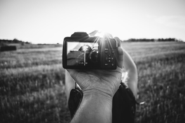 Фото Рука фотографирует женщину в форме сердца на поле.