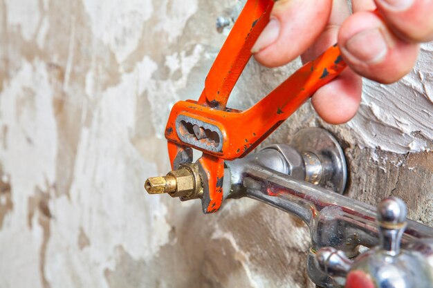 Photo cropped hand of plumber repairing faucet at home