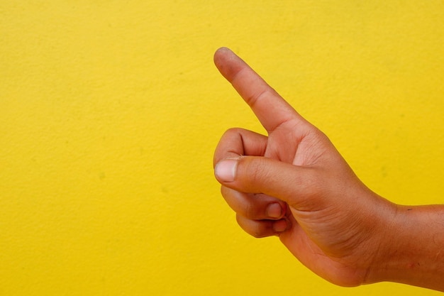 Photo cropped hand pointing against yellow wall