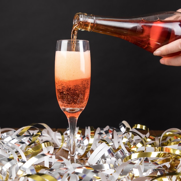 Photo cropped hand pouring drink in champagne flute