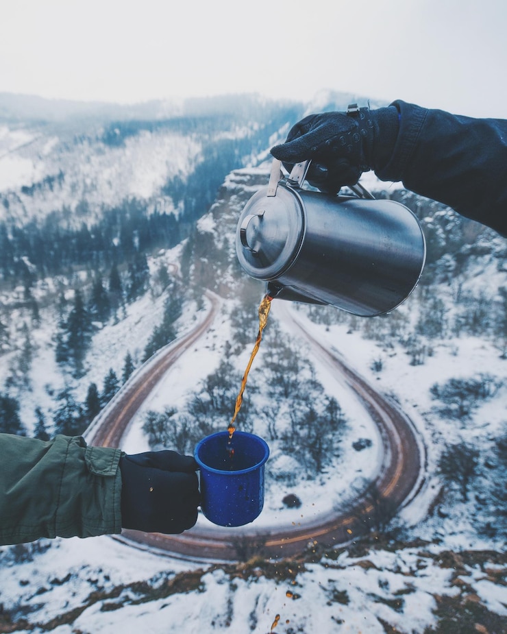 Photo cropped hand pouring tea for friend against mountain