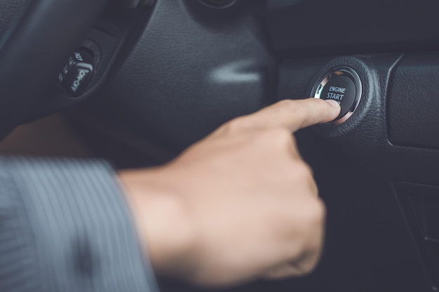 Cropped hand pushing start button in car