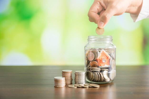 Photo cropped hand putting coin in jar on table