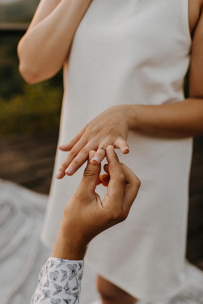 Photo cropped hand putting ring in woman hand outdoors