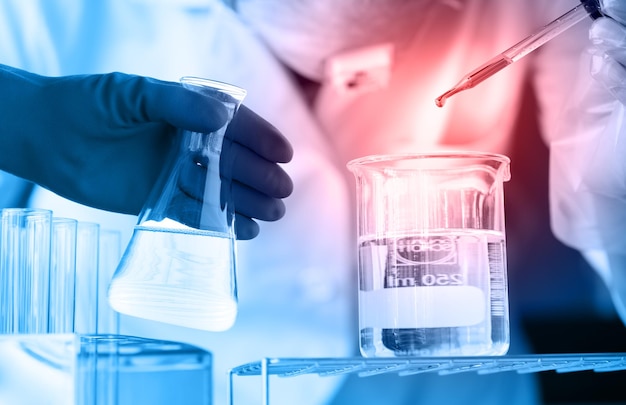 cropped hand of scientist holding chemical in flask at laboratory