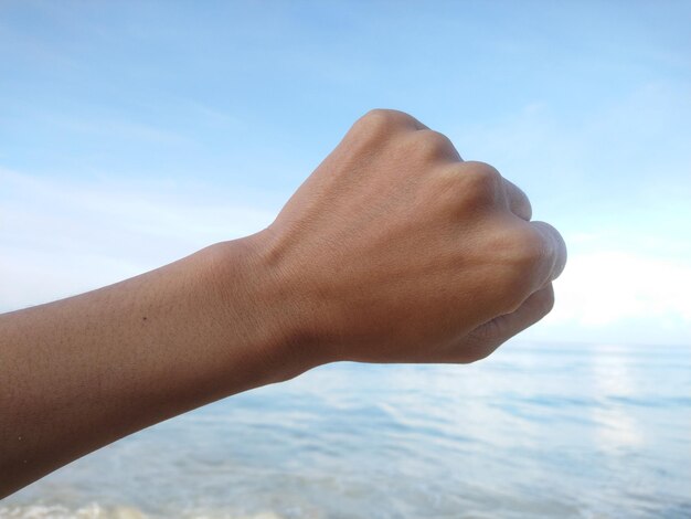 Photo cropped hand over sea against sky