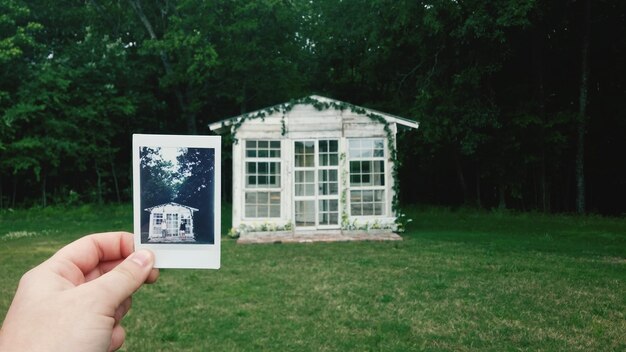 Foto mano tagliata che mostra una fotografia della casa