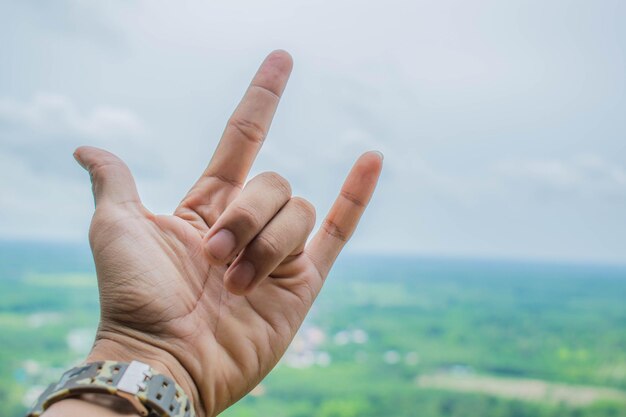 Photo cropped hand showing rock sign against sky