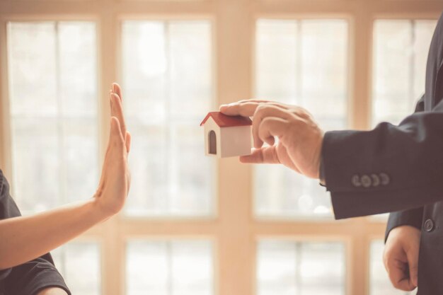 Photo cropped hand showing stop gesture to person holding model home