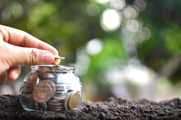 Photo cropped hand stacking coins in glass jar