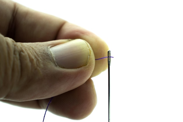 Cropped hand threading needle over white background