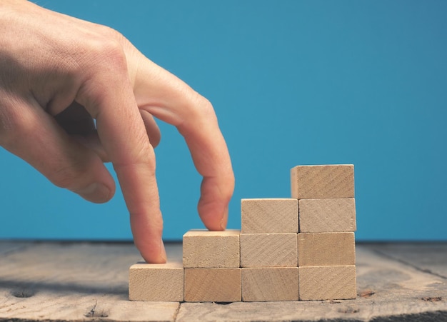 Foto mano tagliata su blocchi di giocattoli su sfondo blu