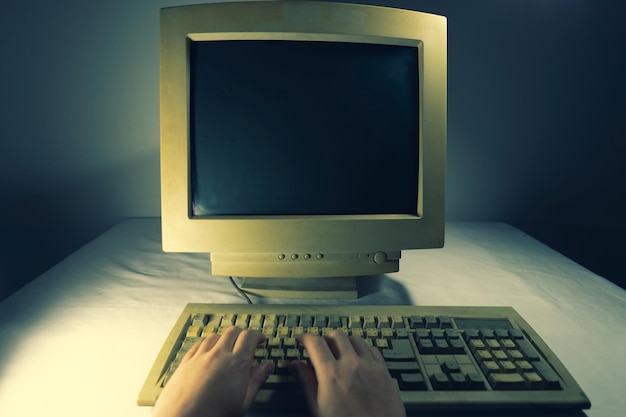 사진 밤 에 테이블 위 에 있는 컴퓨터 키보드 에 손 으로 타이핑 하는 것