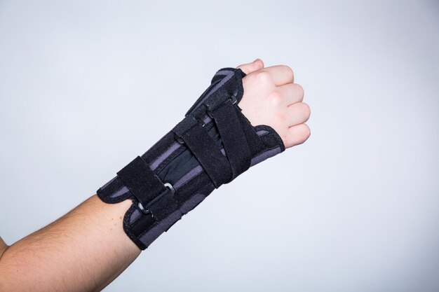 Photo cropped hand wearing orthosis against white background