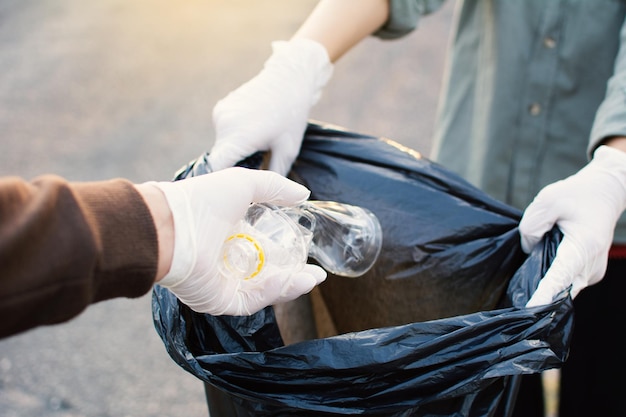プラスチックボトルを袋に入れる際に保護手袋をかぶった手を切り取った
