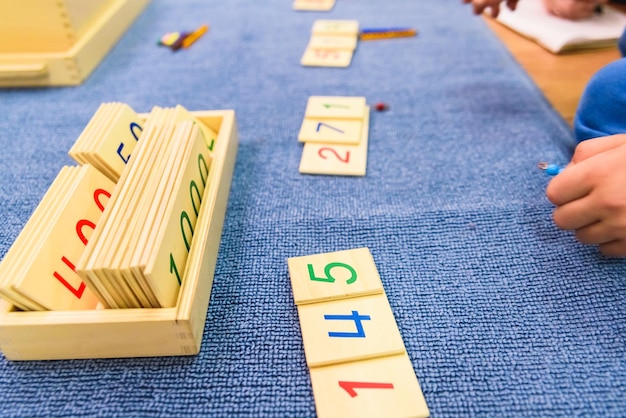 Photo cropped hand with numbers on toy blocks in classroom