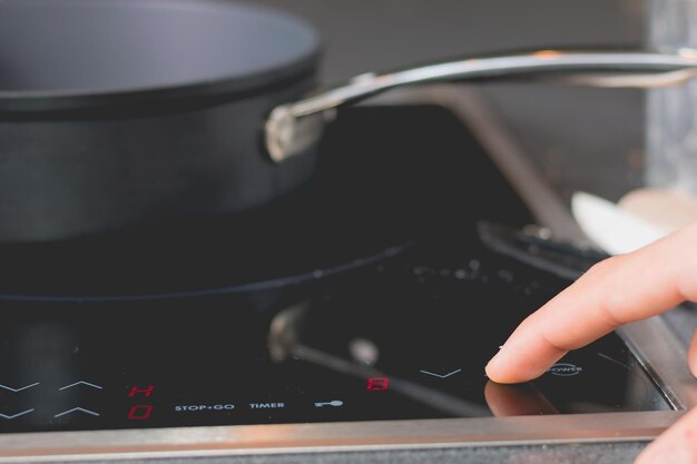 Photo cropped hand with stove in kitchen