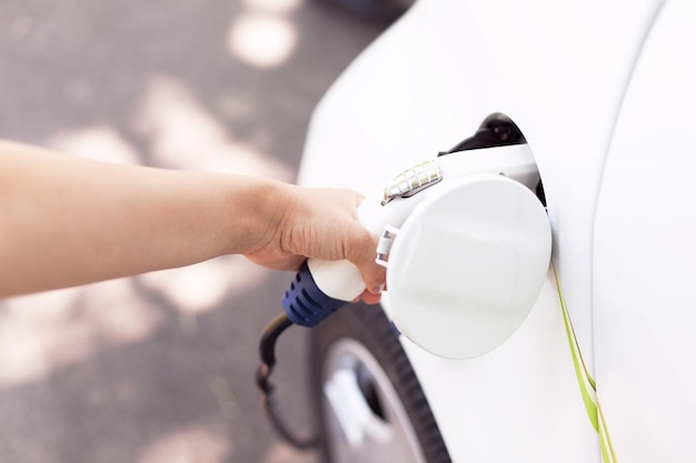 Photo cropped hand of woman charging electric car at station