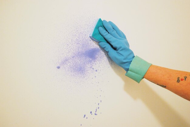 Foto la mano tagliata di una donna che pulisce il muro