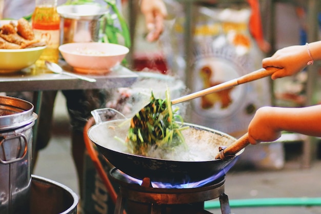 Photo cropped hand of woman cooking food on stove at street