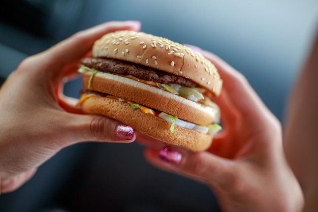 Cropped hand of woman eating hamburger