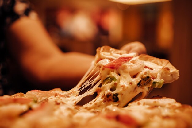 Cropped hand of woman eating pizza