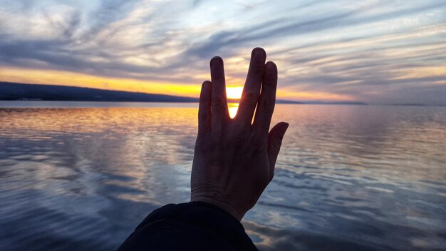 Отрезанная рука женщины, жестикулирующая к морю во время захода солнца