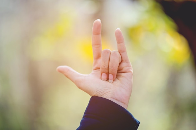 Photo cropped hand of woman gesturing horn sign outdoors