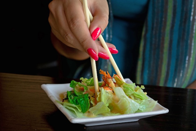 Photo cropped hand of woman having salad at table