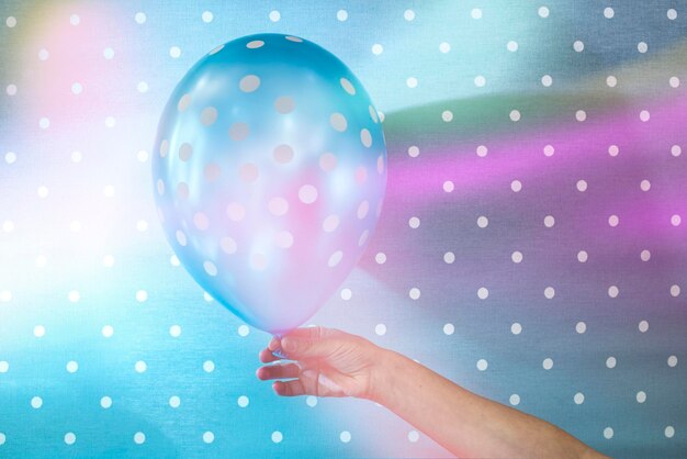 Photo cropped hand of woman holding balloon against curtain