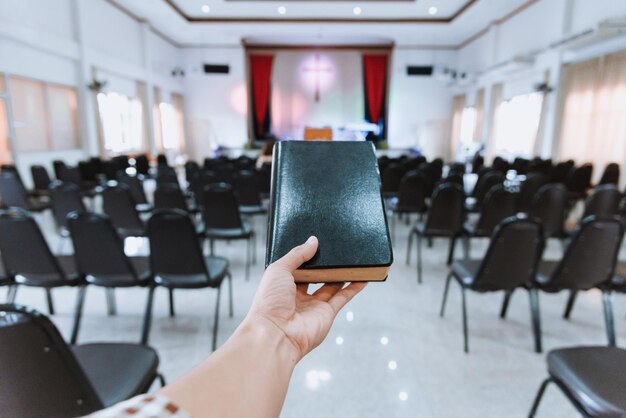 Foto mano tagliata di una donna che tiene la bibbia in chiesa