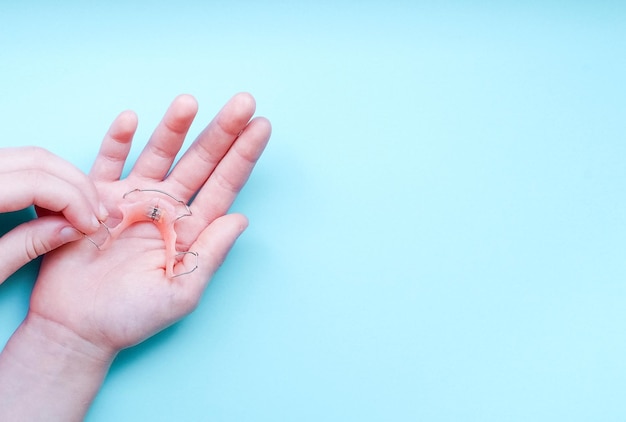 cropped hand of woman holding braces over blue background